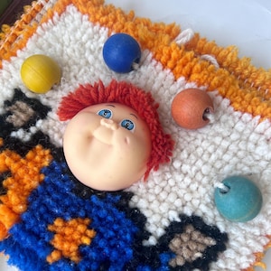 Weird Cabbage-Patch-Doll Inspired Juggling Jester Latch Hook Wall Hanging