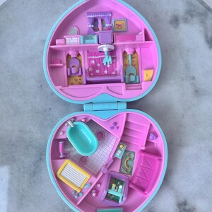 Pu&ograve; includere: Una casetta di giocattolo in plastica rosa e blu a forma di cuore. La casa &egrave; aperta e mostra l'interno, che &egrave; decorato con mobili e accessori. La casa &egrave; un set di gioco per piccole bambole o figurine.