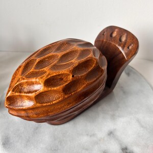 May include: A wooden nutcracker shaped like a nut, with a detailed carved texture. The nutcracker is open, revealing the inside.