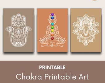 May include: Printable set of three chakra art prints featuring a hamsa hand, a meditating figure with seven chakras, and a mandala with Ganesha. The prints are in white on a beige background.