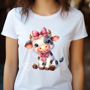 May include: White t-shirt with a cartoon image of a black and white cow wearing a pink bow. The cow is sitting with its legs crossed and has a friendly expression.