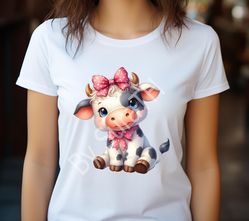May include: White t-shirt with a cartoon image of a black and white cow wearing a pink bow. The cow is sitting with its legs crossed and has a friendly expression.