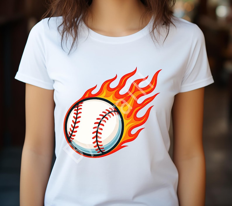 Pode incluir: Camiseta branca com um design de beisebol em chamas. A bola de beisebol &eacute; branca com costuras vermelhas e uma contorno azul, rodeada por chamas laranja e amarelas, criando um gr&aacute;fico esportivo din&acirc;mico.