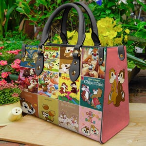 May include: A Chip 'n Dale handbag with a colorful collage design. The bag features a pink side panel and black handles. The front panel displays various Chip 'n Dale comic book covers. The bag has gold-colored hardware and a rectangular shape.