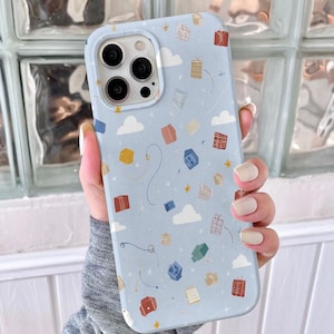 May include: A light blue phone case featuring a pattern of colorful gift boxes, white clouds, and gold stars. The case has a smooth finish and a camera cutout. The design includes whimsical lines and dots.