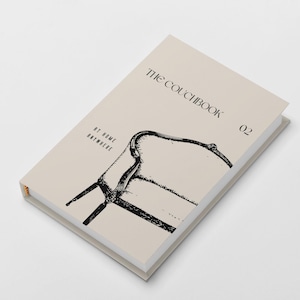Könnte beinhalten: Ein gebundenes Buch mit dem Titel THE COUCHBOOK 02 und dem Untertitel AT HOME ANYWHERE. Der Einband ist hellbeige und zeigt eine schwarze Tuschezeichnung eines Stuhls. Das Buch hat einen weißen Buchrücken und sichtbare weiße Seiten.