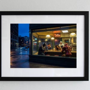 Può includere: Una stampa artistica incorniciata che raffigura una scena notturna all'interno di un diner con Batman, Superman, Wonder Woman e Iron Man seduti al bancone mentre uno chef sta dietro di loro. L'esterno mostra una strada buia e bagnata al crepuscolo.