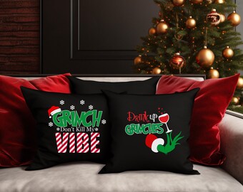Peut inclure: Deux coussins de canapé noirs avec des motifs sur le thème de Noël. Un coussin dit "Grinch Don't Kill My Vibe" avec un motif rayé rouge et blanc. L'autre coussin dit "Drink Up Grinches" avec une main verte tenant un verre de vin.