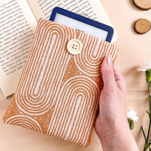 Può includere: Una custodia per e-reader con un motivo marrone e bianco. La custodia è realizzata in tessuto e ha una chiusura a bottone.