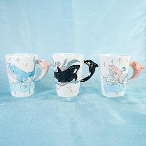 Puede incluir: Tres tazas de cer&aacute;mica con dise&ntilde;os de ballenas y orcas. Cada taza tiene un asa en 3D de ballena u orca.