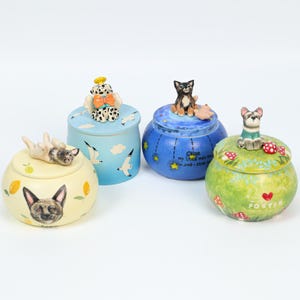 May include: Four decorative ceramic jars with dog-themed designs. The jars are painted in various colors, including yellow, blue, and green, and feature dog figurines on the lids. The jars are decorated with images of lemons, clouds, stars, and mushrooms.