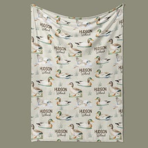 a beige fabric with a repeating pattern of ducks and the name "Hudson Willard" printed on it.