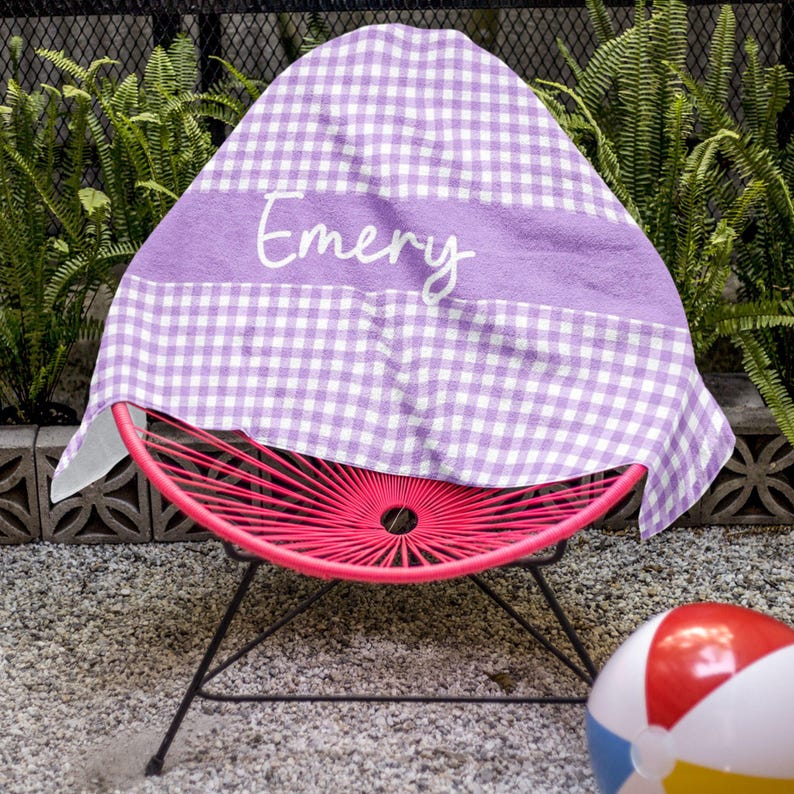 a purple and white towel sitting on top of a pink chair next to a beach