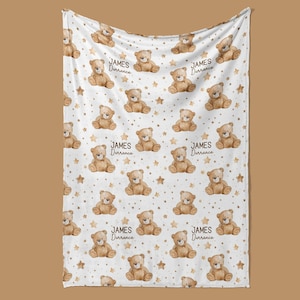 a white blanket with a repeating pattern of brown teddy bears and stars.