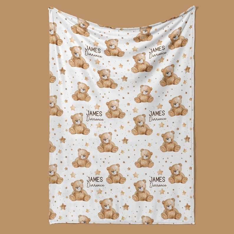 a white blanket with a repeating pattern of brown teddy bears and stars.