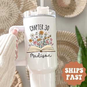 May include: White insulated tumbler with a handle, featuring the text "CHAPTER 30" above an illustration of an open book with flowers and butterflies. The name "Madison" is written below the book.
