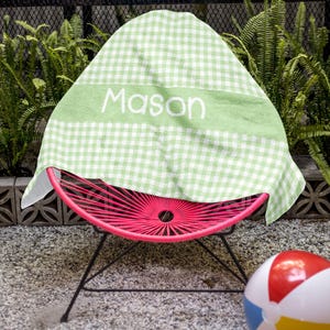 a pink chair with a green and white cover sitting next to a beach ball