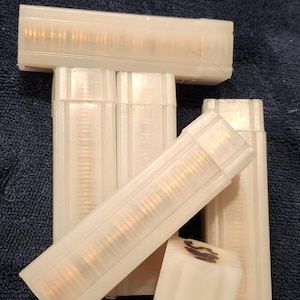 May include: Several clear plastic tubes, each filled with what appears to be gold-colored coins, are arranged on a dark blue surface. The tubes are rectangular and slightly translucent, allowing a glimpse of the contents.