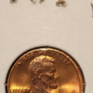 May include: A copper-colored 1981 Lincoln penny. The obverse features a profile of Abraham Lincoln, with the words "LIBERTY" and "IN GOD WE TRUST". The year "1981" is visible.