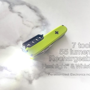 Könnte beinhalten: Ein neongrünes Multitool mit eingebauter Taschenlampe und Pfeife. Das Werkzeug hat 7 Funktionen und ist wiederaufladbar und gibt 55 Lumen ab. Der Text auf dem Bild lautet "7 tools. 55 lumens. Rechargeable Flashlight* & Whistle."