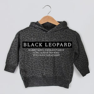 Pode incluir: Camisola de lã polar com capuz para crianças pequenas com estampa de leopardo preto.  "RABBIT SKINS TODDLER FLEECE LONG SLEEVE HOODED PULLOVER SWEATSHIRT" está impresso na frente.