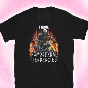 Puede incluir: Camiseta negra con un gráfico de un esqueleto montando una motocicleta a través de llamas. El texto "Tengo tendencias homosexuales" está impreso debajo de la imagen.