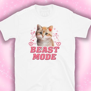 May include: White t-shirt with a cartoon orange tabby cat wearing a pink heart necklace and the text "BEAST MODE" in pink letters.