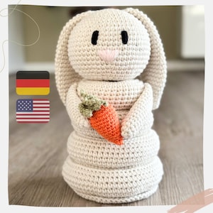 Può includere: Bambola coniglio all'uncinetto beige chiaro, con una carota arancione con foglie verdi. Il coniglio ha occhi neri e un naso rosa. La bambola fatta a mano ha lunghe orecchie.