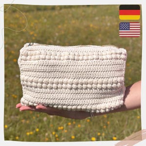May include: A white crocheted pouch with a zipper closure. The pouch has a textured design with small white balls.