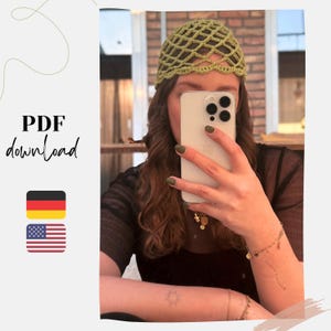 Puede incluir: Un gorro de ganchillo verde claro con un diseño de red. La imagen también incluye el texto "PDF download" y las banderas de Alemania y Estados Unidos.