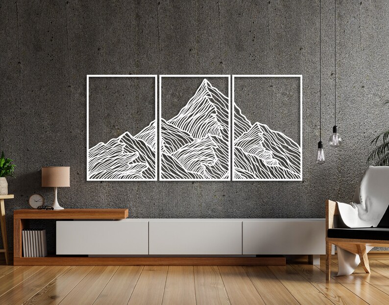 May include: A white metal wall art sculpture depicting a mountain range with a minimalist line art design. The sculpture is divided into three panels and is mounted on a gray wall above a wooden entertainment center.