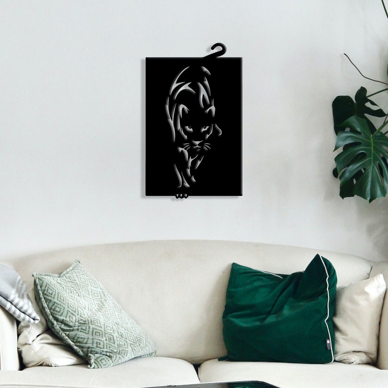 K&ouml;nnte beinhalten: Schwarze Wandkunst aus Metall mit einer stilisierten Silhouette einer Pantherin. Die Pantherin blickt nach vorne, der Kopf leicht geneigt, und ihre Augen schauen direkt auf den Betrachter.