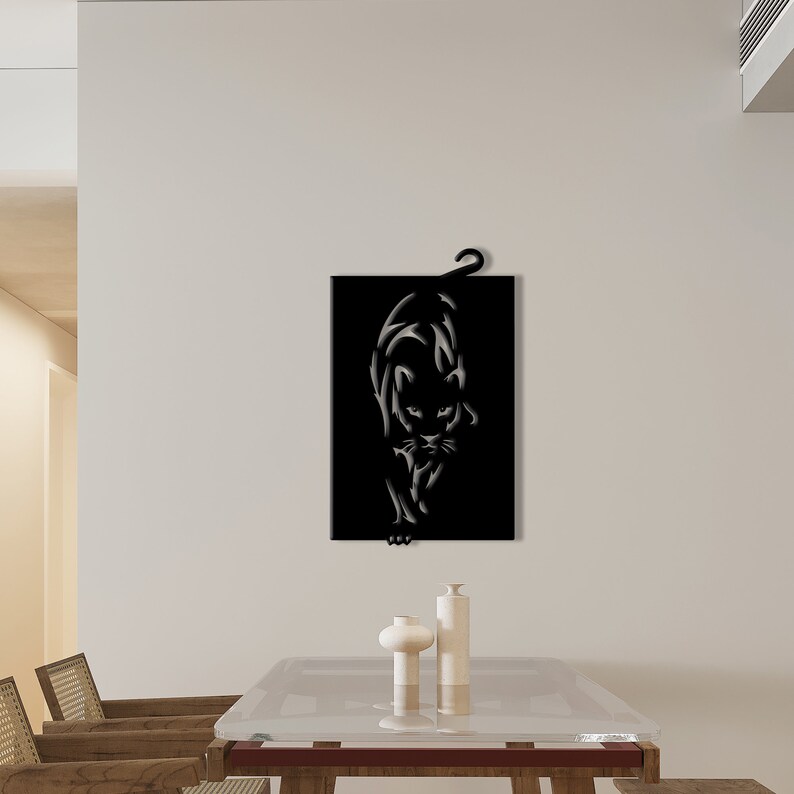 K&ouml;nnte beinhalten: Schwarze Wandkunst aus Metall mit einer stilisierten Silhouette einer Pantherin. Die Pantherin blickt nach vorne, der Kopf leicht geneigt, und der Schwanz ist hinter ihr eingerollt.