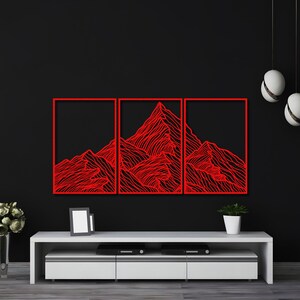May include: Three red metal wall art panels depicting a stylized mountain range. The panels are mounted on a black wall above a white entertainment center.