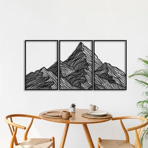 May include: Black metal wall art depicting a stylized mountain range. The art is divided into three panels, each featuring a different section of the mountain range. The art is mounted on a white wall.