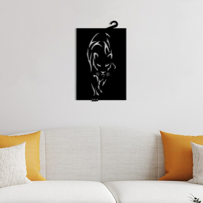 K&ouml;nnte beinhalten: Schwarze Wandkunst aus Metall mit einer stilisierten Silhouette einer Pantherin. Die Pantherin blickt nach vorne, der Kopf leicht geneigt, und der Schwanz ist hinter ihr eingerollt. Die Kunst ist an einer wei&szlig;en Wand montiert.