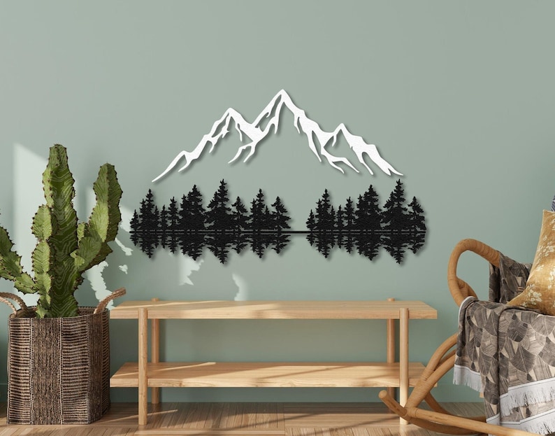 May include: Black metal wall art depicting a mountain range with a reflection of trees in a lake. The mountain peaks are white and the trees are black.