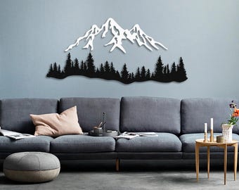 May include: A white silhouette of a mountain range with a forest in front of it, mounted on a light gray wall above a gray couch.