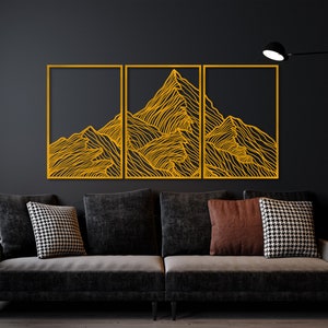 May include: Three rectangular wall art pieces with a black background and a gold outline. The art features a stylized line drawing of a mountain range.