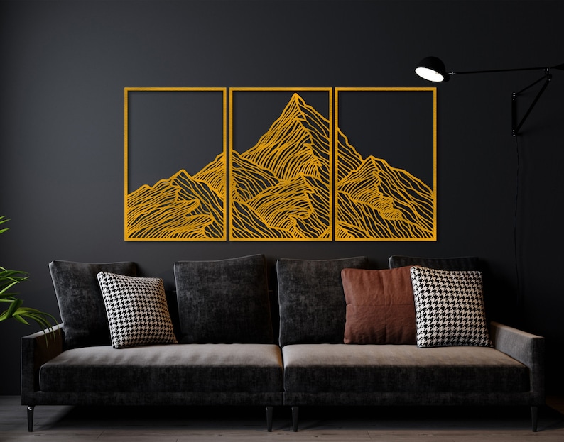 May include: Three rectangular wall art pieces with a black background and a gold outline. The art features a stylized line drawing of a mountain range.