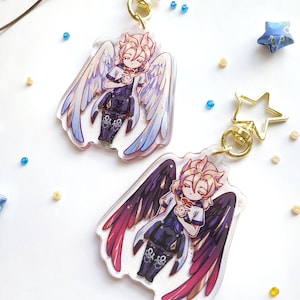 May include: Two acrylic keychains featuring a character with blonde hair and wings. One keychain has white wings with blue accents, and the other has black wings with red accents. Both characters are holding a small, white object.