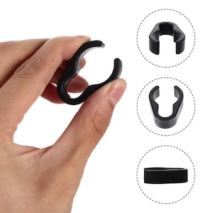 May include: Three black plastic cable clamps. The clamps are shaped like a ring with a small opening on one side. The clamps are used to secure cables and wires.