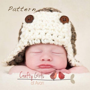 May include: A white and brown crocheted baby hat with brown buttons. The hat has ear flaps and a brim. The hat is on a baby's head. The baby is sleeping. The image has the text "Crafty Girls of Avon" at the bottom.