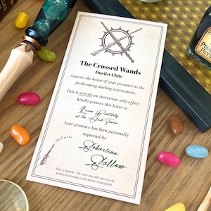 Puede incluir: Una invitación de "The Crossed Wands - Duelist Club" con una varita, una botella de poción y gominolas. La invitación solicita el honor de su presencia en un torneo de duelo. La varita tiene un mango verde y negro.