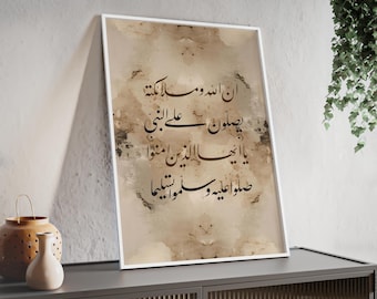 May include: Framed artwork featuring Arabic calligraphy in black script on a beige and brown watercolor-style background. The white-framed print is displayed on a dark gray cabinet. Decorative vases are visible on the cabinet.