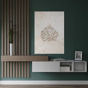 Op de afbeelding: Een witte canvas print met een bruin Arabisch kalligrafieontwerp op een beige marmerachtergrond. De print hangt aan een groene muur boven een wit zwevend rek met boeken en een ingelijste foto.