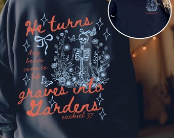 May include: Navy blue sweatshirt with a graphic design on the back featuring a skeleton surrounded by flowers and butterflies. The text reads "He turns dry bones come to life graves into Gardens" and "ezekiel 37". A smaller design is on the front.