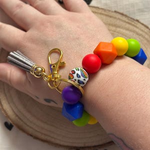 Llavero de pulsera con cuentas de silicona y cierre de mosquetón con estampado animal arcoíris.