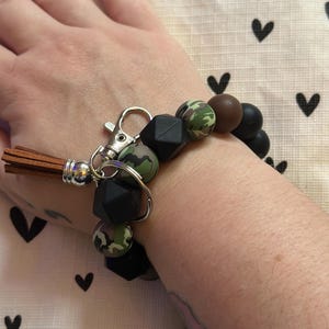 Llavero de pulsera con cuentas de silicona negras y camuflaje y cierre de mosquetón.