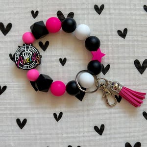 Llavero de pulsera con cuentas de silicona rosa, blanca y negra y cierre de mosquetón.